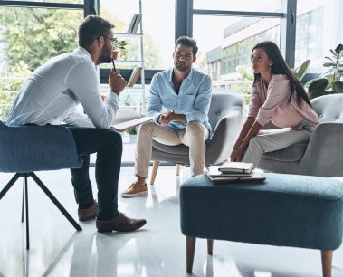 Young married couple talking while sitting on the therapy session with psychologist